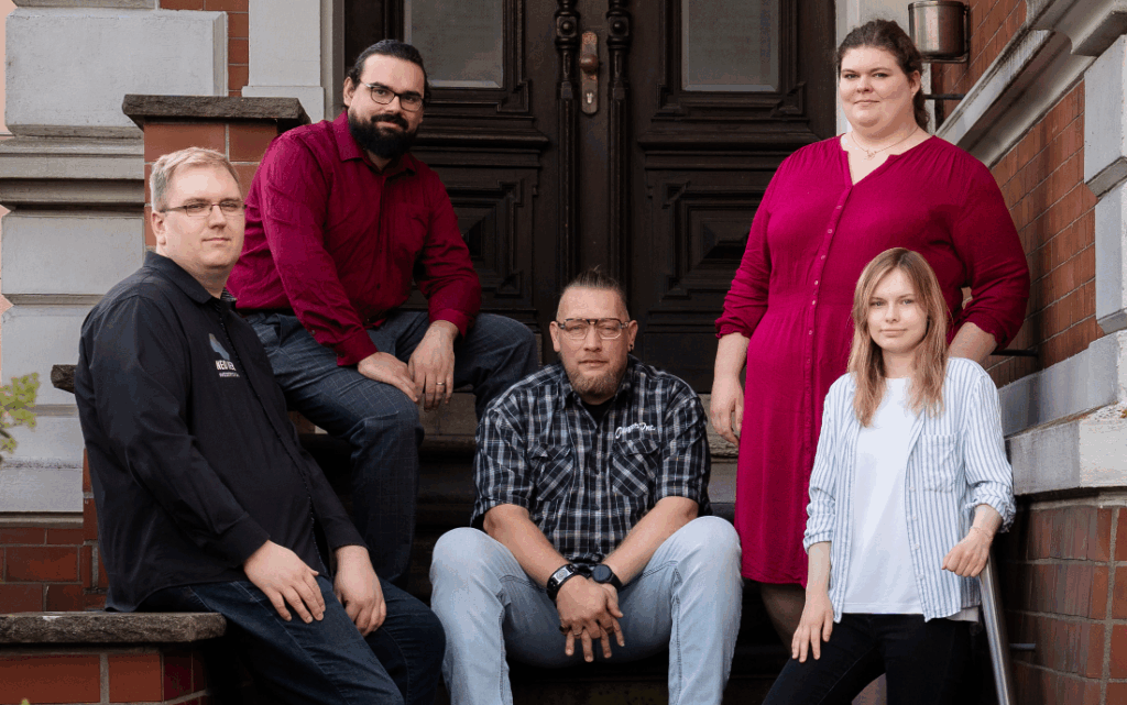 Gruppenfoto des NEOVER Teams vor dem Büro: Kai Rosebrock, Erik Löwen, Marc Beran, Anna Grefe-Löwen und Alicia Wiederspan